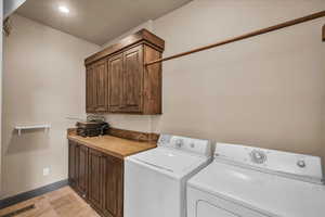Laundry room with cabinet space, separate washer and dryer, and recessed lighting