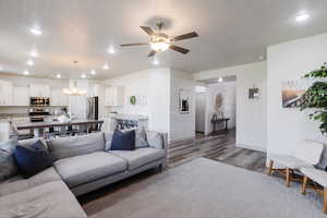 Living room with dark wood-style flooring, ceiling fan, a chandelier, and recessed lighting