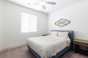 Carpeted bedroom featuring ceiling fan and baseboards
