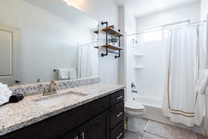 Bathroom featuring vanity, shower / tub combo with curtain, and tile patterned flooring