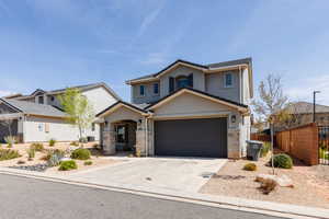 Traditional-style home featuring stucco siding, driveway, stone siding, and a garage