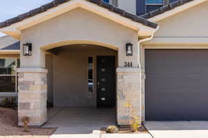 Property entrance with stucco siding, an attached garage, and stone siding