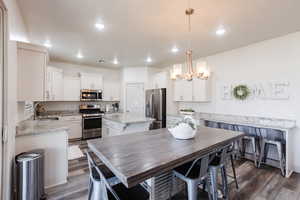 Dining space with dark wood finished floors, a chandelier, and recessed lighting