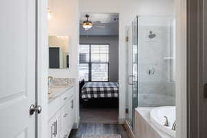 Ensuite bathroom featuring a shower stall, a ceiling fan, a bath, vanity, and wood finished floors