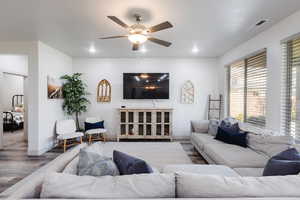 Living room featuring wood finished floors, ceiling fan, plenty of natural light, and recessed lighting