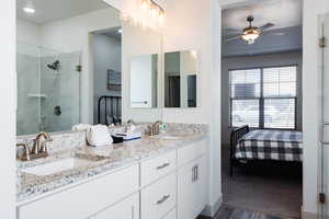 Full bath with connected bathroom, double vanity, a stall shower, ceiling fan, and wood finished floors