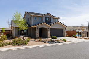 Traditional-style house featuring stucco siding, driveway, stone siding, and an attached garage