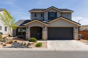 View of front of home with stucco siding, concrete driveway, stone siding, and a garage