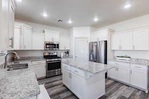 Kitchen with stainless steel appliances, dark wood-style floors, white cabinets, a kitchen island, and recessed lighting