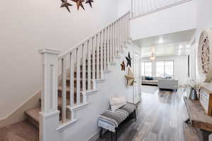 Stairs with wood finished floors, a towering ceiling, and a ceiling fan