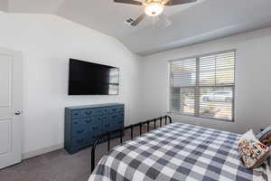 Carpeted bedroom with vaulted ceiling and a ceiling fan
