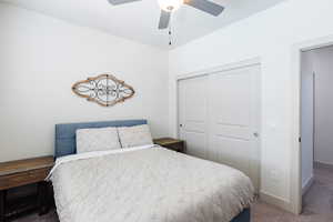 Carpeted bedroom featuring a closet and a ceiling fan