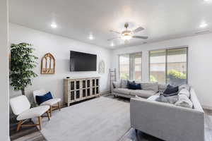Living area with ceiling fan, wood finished floors, and recessed lighting