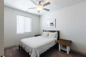 Bedroom with dark colored carpet and a ceiling fan