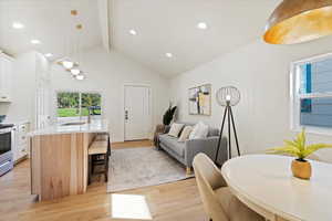 Living area with beam ceiling, light wood finished floors, recessed lighting, and high vaulted ceiling