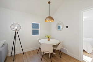 Dining area featuring light wood-type flooring and vaulted ceiling