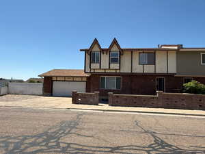View of front of house featuring an attached garage, concrete driveway, and brick siding