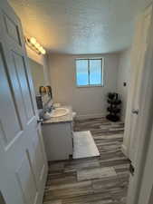 Bathroom with vanity, wood finished floors, a textured ceiling, baseboards, and toilet