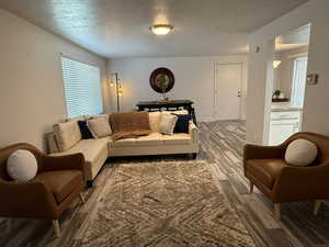 Living room featuring wood finished floors, a textured ceiling, and baseboards