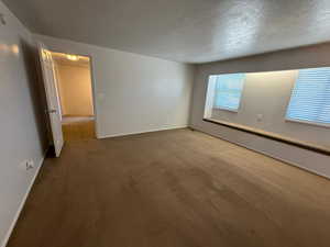 Unfurnished room with carpet flooring, baseboards, and a textured ceiling