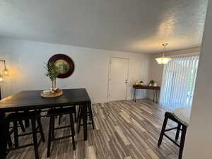 Dining space featuring dark wood-style floors, a textured ceiling, and baseboards