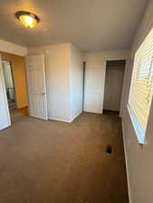 Unfurnished bedroom featuring carpet, baseboards, a closet, and a textured ceiling