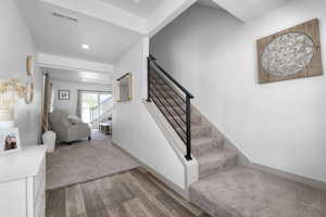 Stairway with wood finished floors, recessed lighting, and carpet flooring