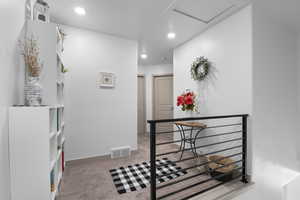 Hall with carpet, an upstairs landing, attic access, and recessed lighting