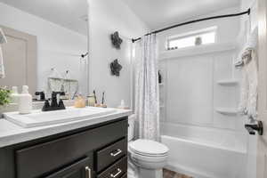 Full bath with vanity, shower / bath combo, and wood finished floors