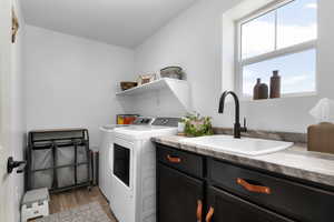 Laundry area with washer and dryer, cabinet space, and wood finished floors