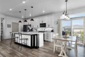 Kitchen with freestanding refrigerator, recessed lighting, wood finished floors, an island with sink, and light countertops