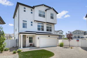 View of front of home with a garage, driveway, a gate, and a residential view