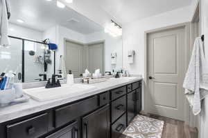 Full bathroom featuring double vanity, wood finished floors, and a shower stall