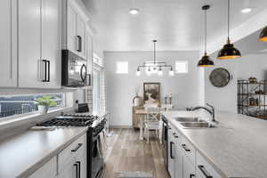 Kitchen featuring stainless steel appliances, light countertops, light wood finished floors, pendant lighting, and healthy amount of natural light