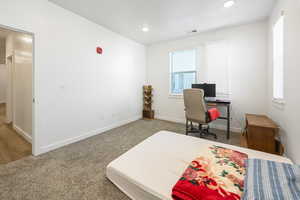 Carpeted bedroom with recessed lighting and an office area