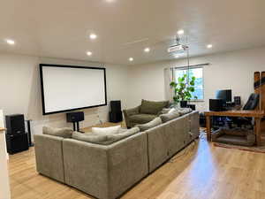 Home theater room with light wood finished floors and recessed lighting
