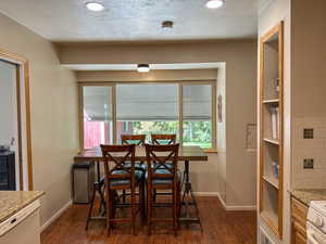 Dining room featuring dark wood finished floors, recessed lighting, and a textured ceiling