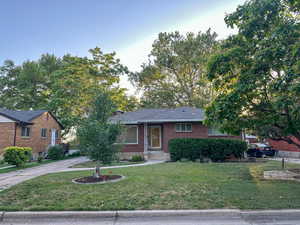 Ranch-style house featuring a front lawn, brick siding, and concrete driveway