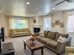 Living room featuring healthy amount of natural light, ceiling fan, recessed lighting, carpet flooring, and a fireplace