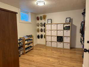 Wine room with light wood finished floors and a textured ceiling