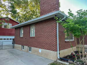 View of home's exterior featuring a garage, brick siding, and a chimney
