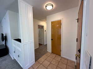 Hall featuring light colored carpet and light tile patterned floors
