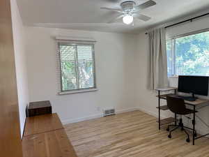 Office with healthy amount of natural light, wood finished floors, and a ceiling fan