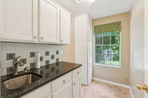 Kitchen with decorative backsplash, white cabinetry, dark stone counters, and a textured ceiling
