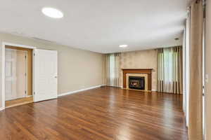 Unfurnished living room featuring wood finished floors, a fireplace with flush hearth, and a textured ceiling