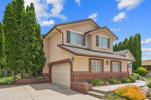 View of front facade featuring a garage, stucco siding, and driveway