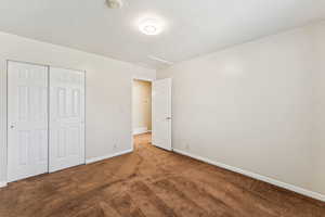 Unfurnished bedroom featuring carpet, a closet, attic access, and a textured ceiling