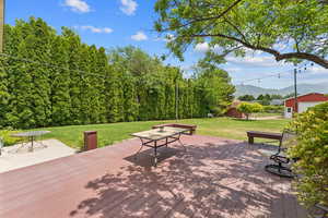 Deck featuring a mountain view, a lawn, and an outbuilding