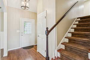 Foyer entrance with stairs, wood finished floors, and a chandelier