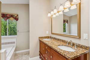 Full bath with double vanity, a chandelier, and a relaxing tiled tub